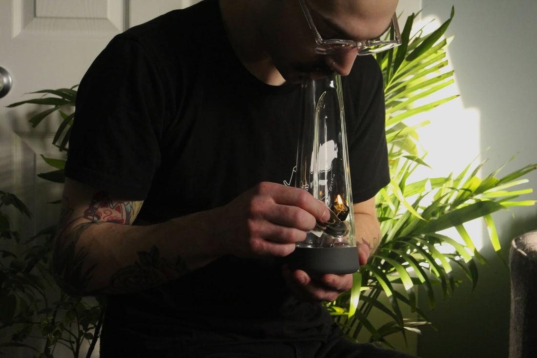 man with glasses holding bong to mouth smoking